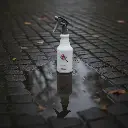 Heavy Duty BROTHERS Spray Bottle 650ML placed outdoors on a wet cobblestone street - بخاخ خدمة شاقة براذرز التايواني في الشارع جنب بركة ماية
